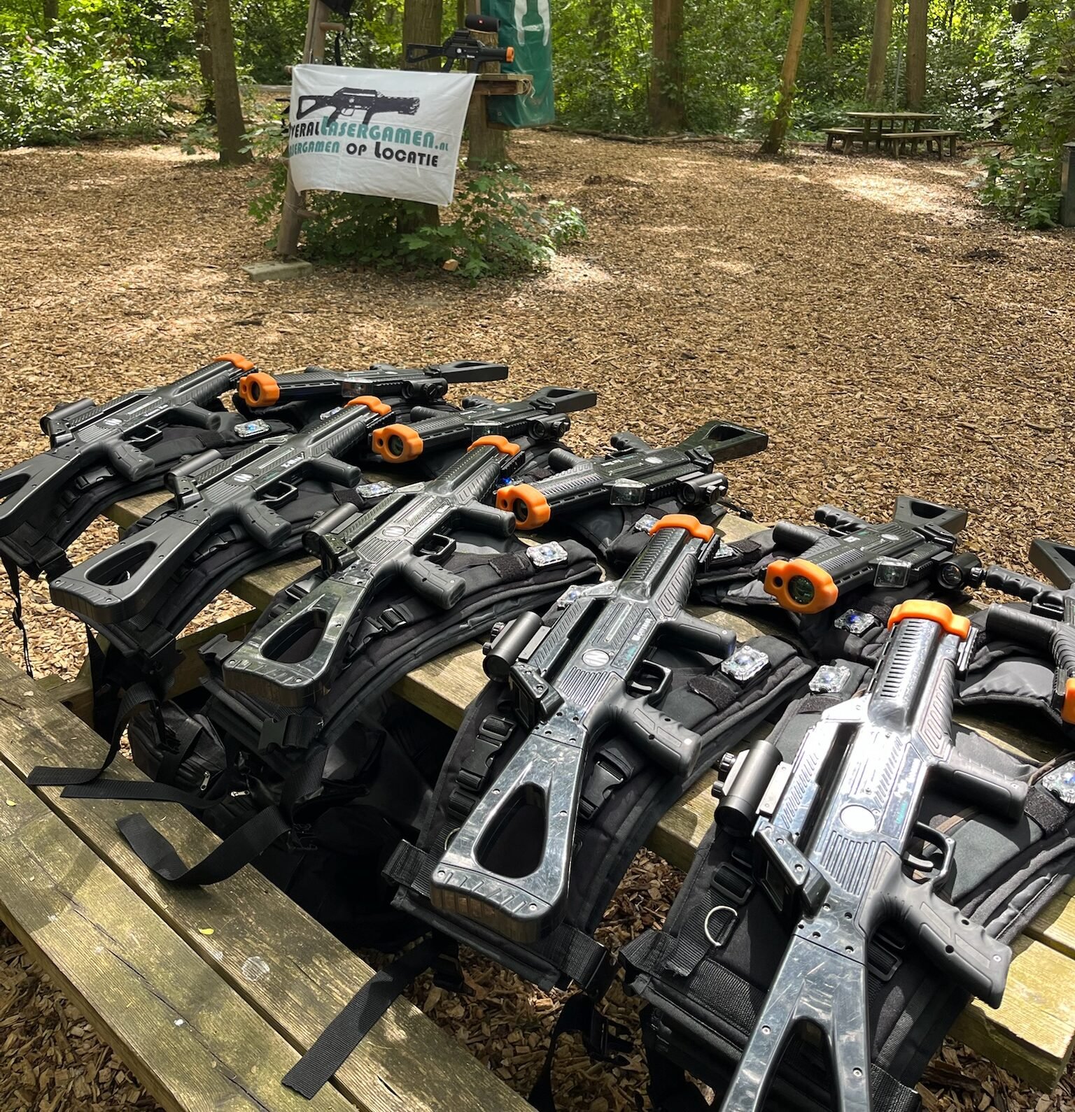 Lasergame activiteit op een buitenterrein met natuurlijke obstakels van bomen en struiken.